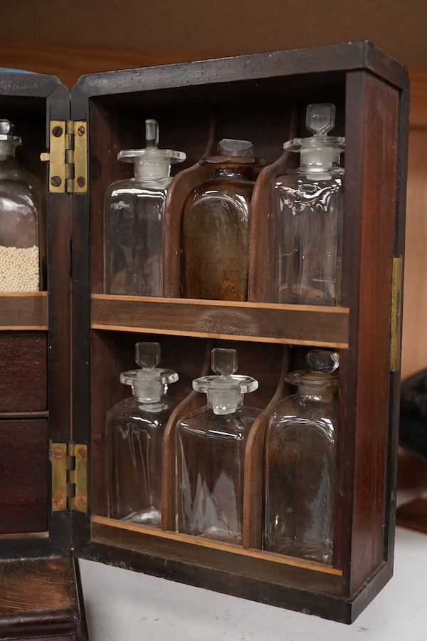 A 19th century mahogany apothecary cabinet, interior with fitting compartments containing twenty-one glass bottles, most with stoppers, five drawers with ivory knobs containing a miniature pestle and water, mixing glasse